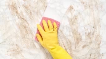 gloved hand cleaning marble countertop with sponge