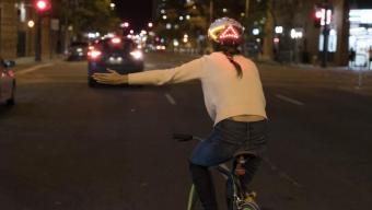Woman on bike wearing Lumos smart bike helmet