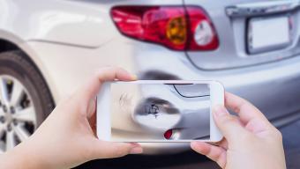 person using smartphone to photograph damage to car