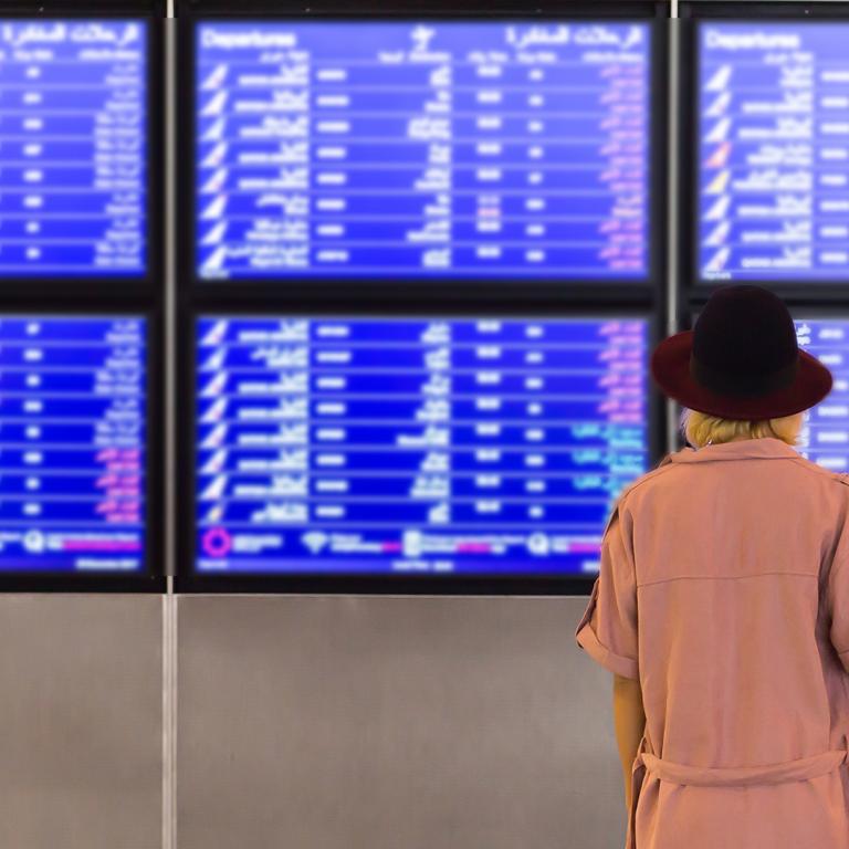 Woman looking at airport departures/arrivals board