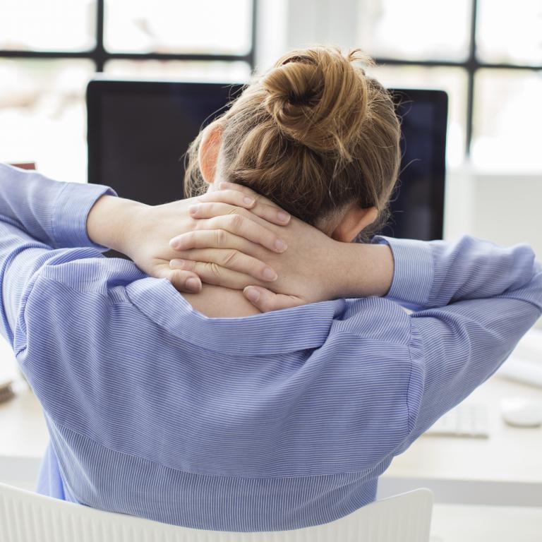 woman at desk stretching her back