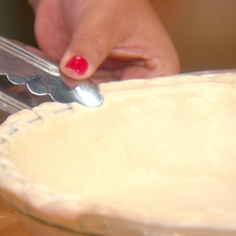 using tongs to make pattern on pie crust dough