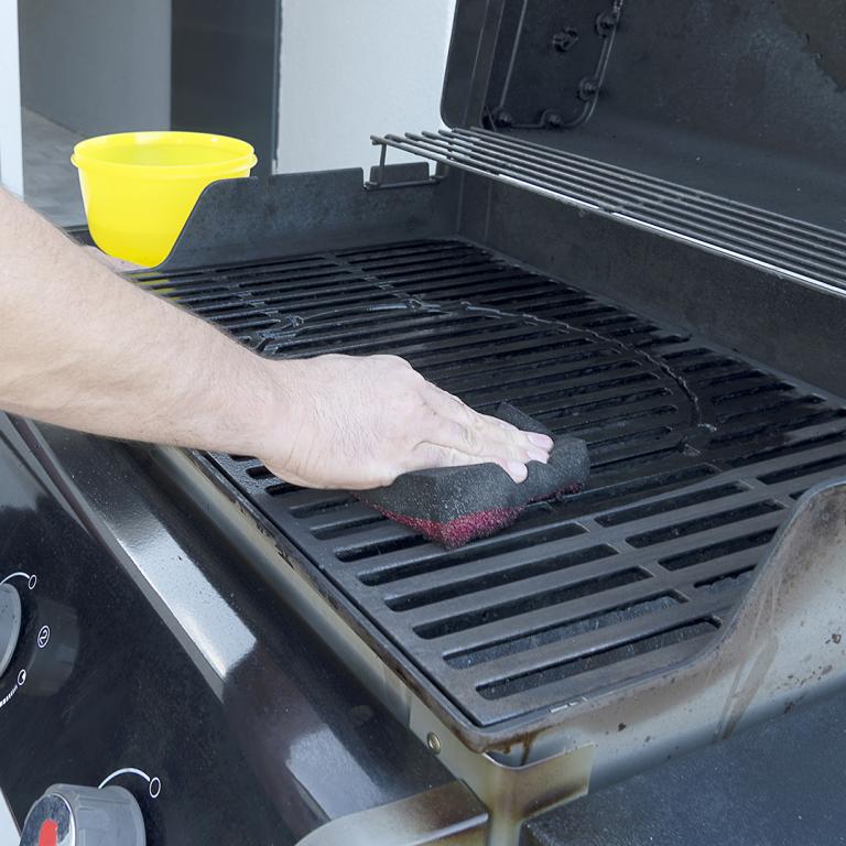 person cleaning gas grill