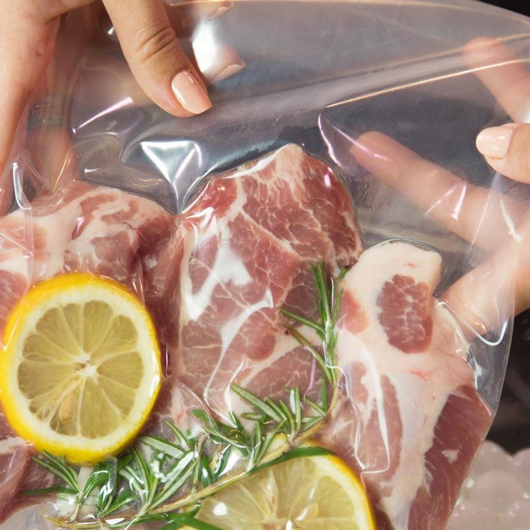 freezer bag with raw meat, lemons and rosemary