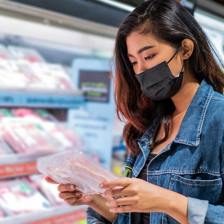 woman with mask shopping for meat